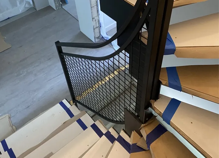 Schody zabiegowe z drewnianymi stopniami i stalową balustradą w trakcie montażu